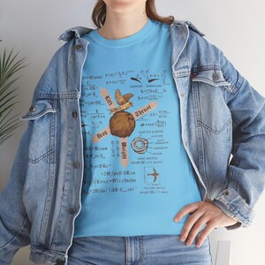 May include: A light blue t-shirt with a complex graphic design incorporating scientific diagrams and equations. The central image is a brown sphere with a bird, and the words "Lift", "Thrust", "Drag", and "Weight".