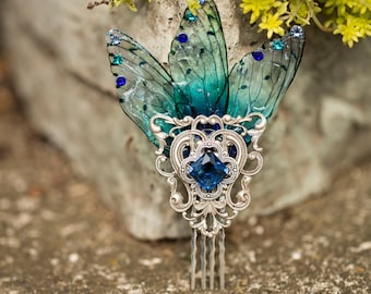 May include: A silver hair comb with a blue gemstone and two blue and green butterfly wings.