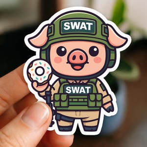 May include: A die-cut sticker featuring a cartoon pig wearing a green SWAT helmet and vest. The pig is holding a donut with white frosting and sprinkles. The word "SWAT" is printed on the helmet and vest.