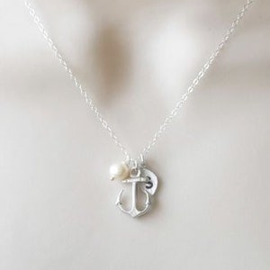 May include: A silver necklace with a small anchor charm, a pearl, and a heart charm.