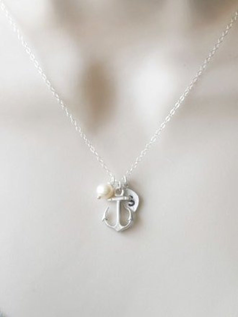 May include: A silver necklace with a small anchor charm, a pearl, and a heart charm.