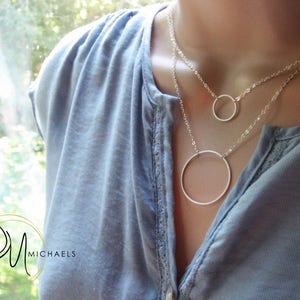 May include: A silver necklace with two circle pendants. The larger circle is about 2 inches in diameter and the smaller circle is about 1 inch in diameter.