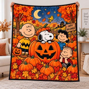 May include: A rectangular fleece blanket featuring a Peanuts Halloween scene with Charlie Brown, Snoopy in a pumpkin, Lucy, and Linus surrounded by orange pumpkins and autumn leaves under a crescent moon, with a sign reading Happy Halloween.