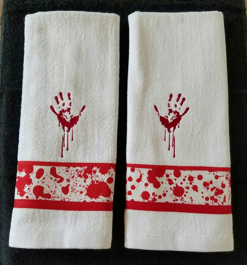 May include: Two white hand towels with red embroidered bloody handprints and red and white bloody splatter designs.