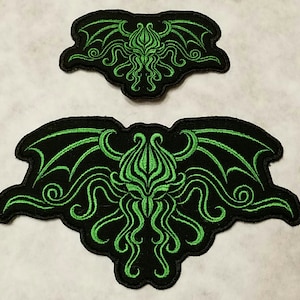 May include: Two black and green embroidered patches featuring a stylized Cthulhu design. The larger patch is approximately 10 inches wide and the smaller patch is approximately 5 inches wide.