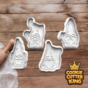 May include: Four white plastic gnome-shaped cookie cutters. Each cutter features a different gnome design, with details like hats, beards, and tools. The Cookie Cutter King logo is in the bottom right corner.