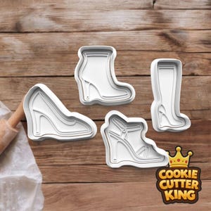 May include: Four white plastic cookie cutters shaped like high-heeled shoes and boots. The cutters include a wedge heel, ankle boot, sandal, and knee-high boot. The Cookie Cutter King logo is in the bottom right corner.