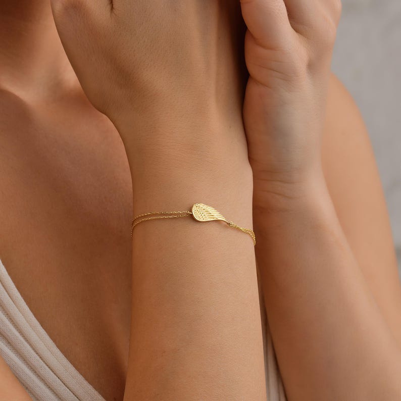 Pode incluir: Uma delicada pulseira dourada com um berloque em forma de pena. A pulseira tem um design de corrente fina e &eacute; usada no pulso. O berloque de pena tem detalhes intrincados, adicionando um toque de eleg&acirc;ncia &agrave; joia.