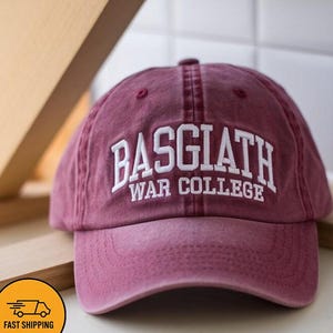 以下が含まれることがあります： 「BASGIATH WAR COLLEGE」の白文字が入った、マルーン色のベースボールキャップ。カーブしたつばと6パネルのデザイン。柔らかく使い古された素材で作られています。