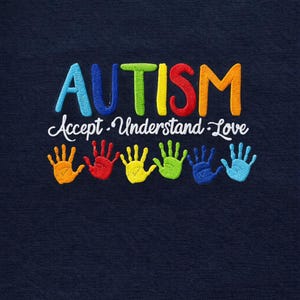 May include: Navy blue fabric with embroidered text and handprints. The word "AUTISM" is in colorful letters above the words "Accept. Understand. Love." Below are six handprints in various colors, including orange, red, yellow, green, blue, and light blue.