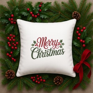 May include: A white square pillow with the embroidered text "Merry Christmas" in red and green, decorated with holly leaves and berries. The pillow is surrounded by a festive arrangement of pine branches, red berries, pine cones, and a red ribbon.