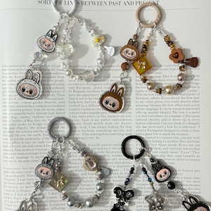 May include: A selection of charm keyrings with cartoon bunny faces, pearls, and decorative charms. The keyrings have a variety of colours and shapes, with a focus on a cute, playful aesthetic.