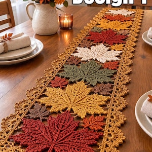 May include: A long, rectangular crochet table runner featuring a repeating pattern of maple leaves in shades of red, orange, yellow, brown, green, and cream, bordered by a delicate scalloped edge. The text Design 1 is visible.