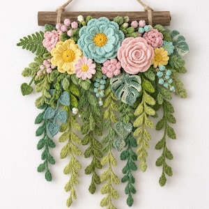 May include: A wall hanging featuring a collection of crocheted flowers and foliage attached to a horizontal wooden branch with a jute twine hanger. The arrangement includes light blue, yellow, and pink blossoms with various green leaves.
