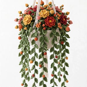 May include: A crocheted hanging plant in a cream-colored macrame holder. The plant features vibrant yellow, red, and pink crocheted flowers, small orange berries, and long, trailing green crocheted vines with detailed leaves.