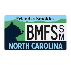 May include: A rectangular sticker with a blue and green background. The sticker features the text "Friends of the Smokies" and "North Carolina". A black bear silhouette is on the left side, with the letters "BMFS" in the center.