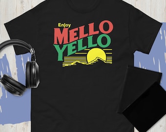 Może przedstawiać: Czarna koszulka z napisem "Enjoy Mello Yello" w kolorze czerwonym i zielonym, z żółtą grafiką słońca nad pasmem górskim. Koszulka ma krótkie rękawy i okrągły dekolt.