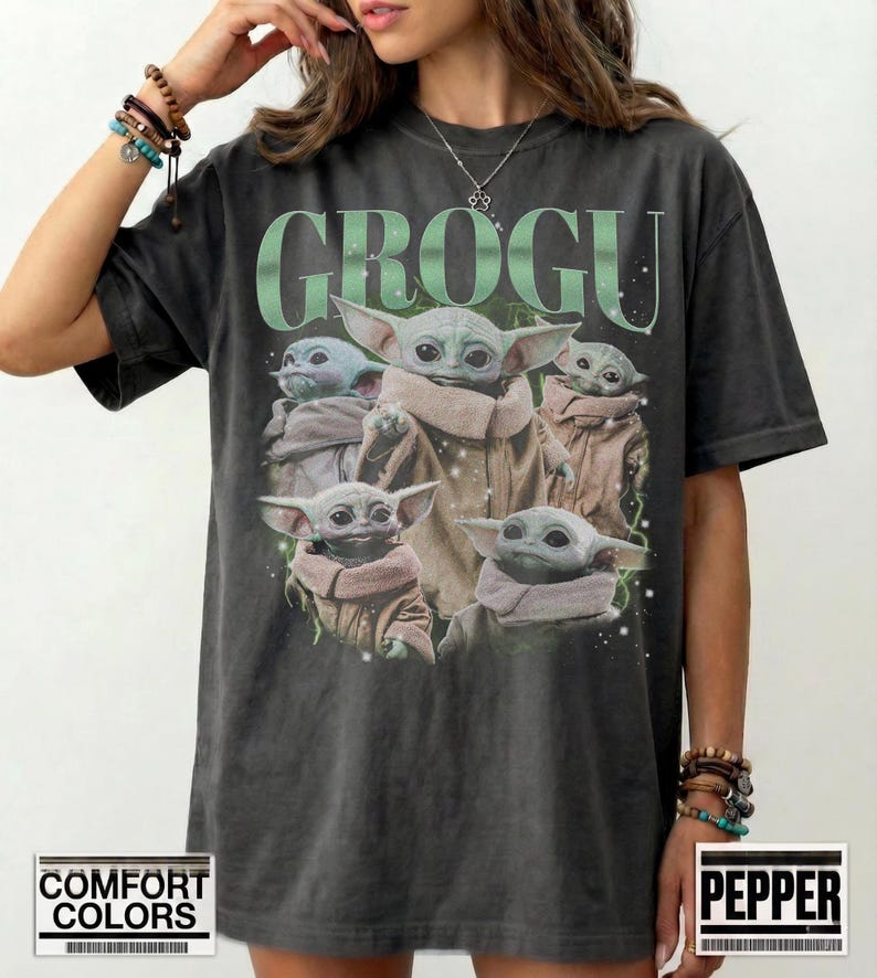 Puede incluir: Camiseta gris oscuro con la palabra "GROGU" en verde sobre un gr&aacute;fico de Grogu, tambi&eacute;n conocido como Baby Yoda, de The Mandalorian. El gr&aacute;fico muestra a Grogu en varias poses. La camiseta es de la marca Comfort Colors.
