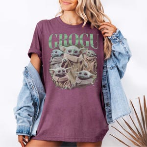 Puede incluir: Camiseta granate con un dise&ntilde;o de Grogu de The Mandalorian. El dise&ntilde;o incluye m&uacute;ltiples im&aacute;genes de Grogu y la palabra "GROGU" en letras verdes. La camiseta tiene mangas cortas y un corte holgado.