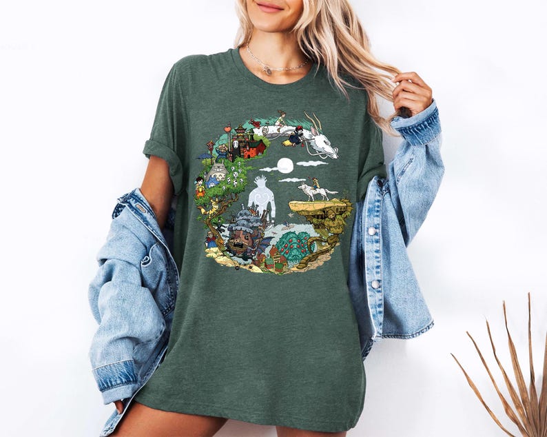 May include: Dark green t-shirt with a vibrant circular graphic. The design showcases animated characters, buildings, and a white dragon. The t-shirt has short sleeves and a relaxed fit, suitable for casual wear.