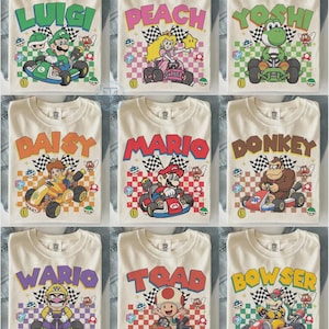 May include: A collection of nine off-white t-shirts, each featuring a different Nintendo character driving a go-kart. Characters include Luigi, Peach, Yoshi, Daisy, Mario, Donkey Kong, Wario, Toad, and Bowser, all set against a checkered background.
