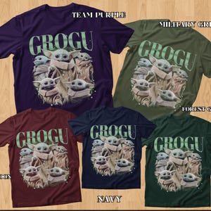 Puede incluir: Una colecci&oacute;n de camisetas de Grogu en varios colores: morado equipo, verde militar, verde bosque, granate, azul marino. Cada camiseta presenta un gr&aacute;fico de Grogu y la palabra "GROGU" en verde.
