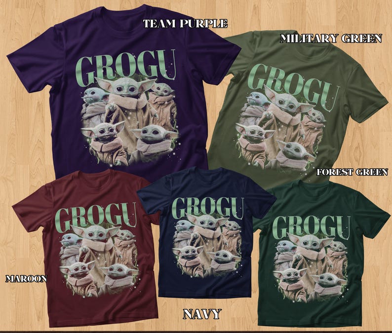 Puede incluir: Una colecci&oacute;n de camisetas de Grogu en varios colores: morado equipo, verde militar, verde bosque, granate, azul marino. Cada camiseta presenta un gr&aacute;fico de Grogu y la palabra "GROGU" en verde.