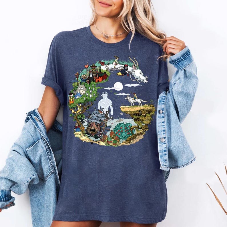 May include: Navy blue t-shirt with a vibrant graphic design depicting scenes and characters from an animated film. The design includes a white dragon, a castle, and other elements. The shirt is made of soft material.