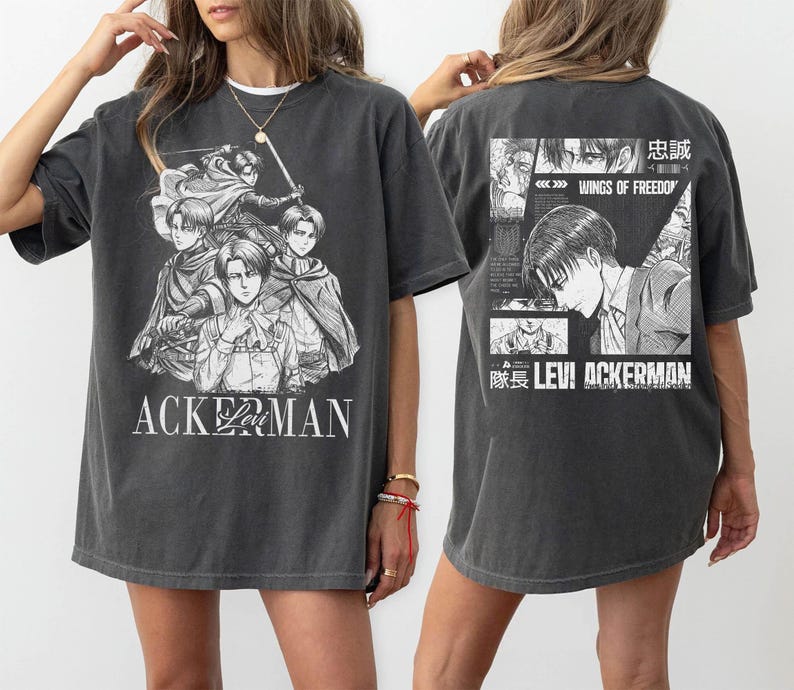 May include: Dark gray t-shirt featuring a black and white graphic of anime characters with the text "ACKERMAN" on the front. The back of the shirt has a graphic with the text "WINGS OF FREEDOM" and "LEVI ACKERMAN".
