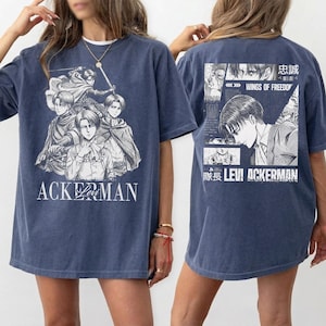 May include: A blue t-shirt featuring a graphic of anime characters with the text "ACKERMAN" on the front. The back of the shirt displays additional anime graphics and the text "WINGS OF FREEDOM" and "LEVI ACKERMAN".