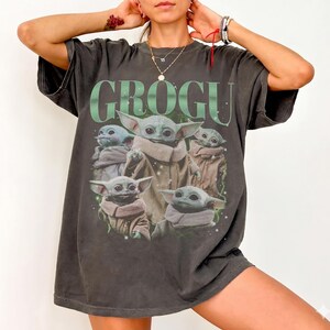 Puede incluir: Camiseta gris oscuro con un gr&aacute;fico de Grogu, tambi&eacute;n conocido como Baby Yoda, de The Mandalorian. La palabra "GROGU" est&aacute; impresa en verde encima de la imagen de Grogu. La camiseta tiene un aspecto vintage y desgastado.