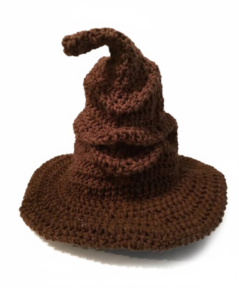Peut inclure: Un chapeau marron crochet&eacute; avec un large bord et un sommet pointu. Le chapeau est fait d'un fil textur&eacute; et a une pointe l&eacute;g&egrave;rement incurv&eacute;e. Le chapeau est de couleur marron uni et est probablement un &eacute;l&eacute;ment de costume.