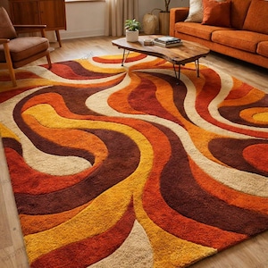 May include: A large, retro-style rug with a swirling pattern in shades of orange, yellow, brown, and beige. The rug's design features flowing, organic shapes, creating a warm aesthetic. Suitable for living rooms and other interior spaces, this rug is a statement piece.