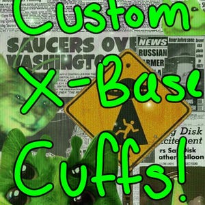 May include: A collage featuring green alien cat faces, newspaper clippings, and a yellow hazard sign. Bold green text spells "Custom X-Base Cuffs!" with a retro, comic book style.