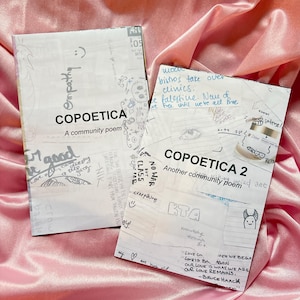 Puede incluir: Dos fanzines de poemas comunitarios titulados "COPOETICA" y "COPOETICA 2" con notas y dibujos manuscritos. Los fanzines están sobre una superficie de satén rosa. El primer fanzine dice "Empathy" y "A community poem". El segundo dice "Another community poem".