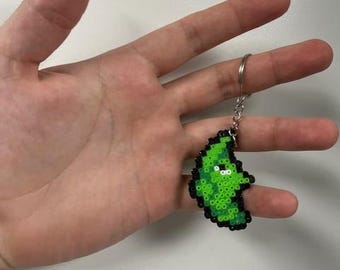 May include: A green and black beaded keychain in the shape of a leaf. The keychain is made of small, colorful beads and has a silver keyring attached. The leaf design features a lighter green center and a darker green outline.