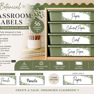 May include: A set of printable classroom labels featuring a botanical greenery design. The labels are displayed on four olive green plastic storage trays stacked in a wooden organiser. The labels include text such as Paper, Coloured Paper, Card, and Scrap Paper.