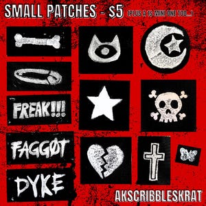 Puede incluir: Una colección de pequeños parches cuadrados negros con diseños blancos. Los parches presentan un hueso, un ojo, una luna creciente y una estrella, un imperdible, una estrella, una calavera y huesos cruzados, la palabra "FREAK!!!", un corazón roto, una cruz, una mariposa y las palabras "FAGGOT" y "DYKE".