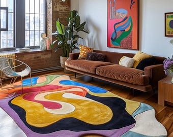 May include: A colorful, abstract area rug with a unique, organic shape. The rug features a vibrant palette of purple, yellow, blue, red, and black. It's placed in a living room with a brown velvet sofa and a large window.