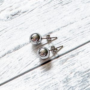 May include: A pair of silver ball stud earrings. The earrings are simple and elegant, and they would make a great gift for any occasion.
