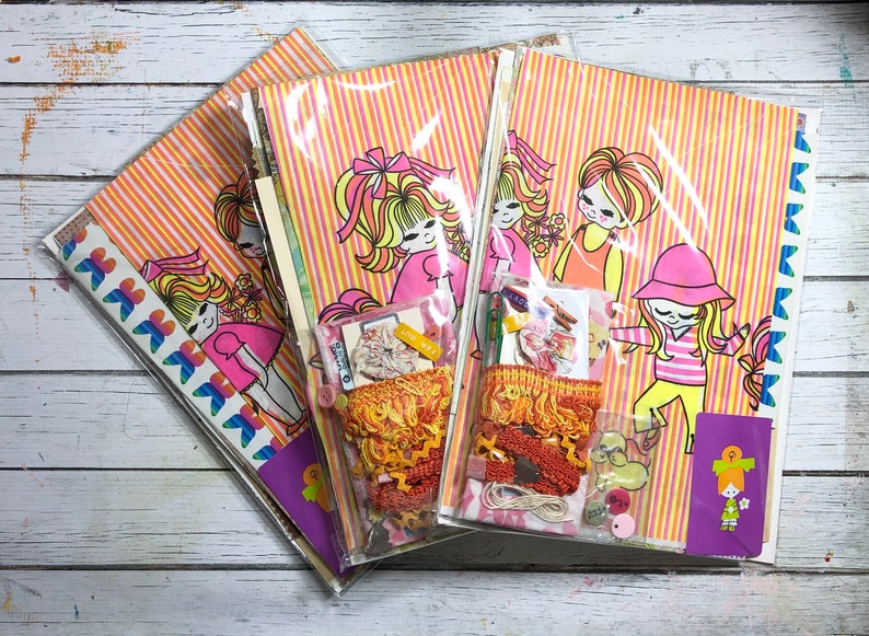 May include: Three sets of colorful patterned paper with illustrations of girls with long hair and bright clothing. Each set includes a variety of embellishments, including ribbons, lace, and buttons.