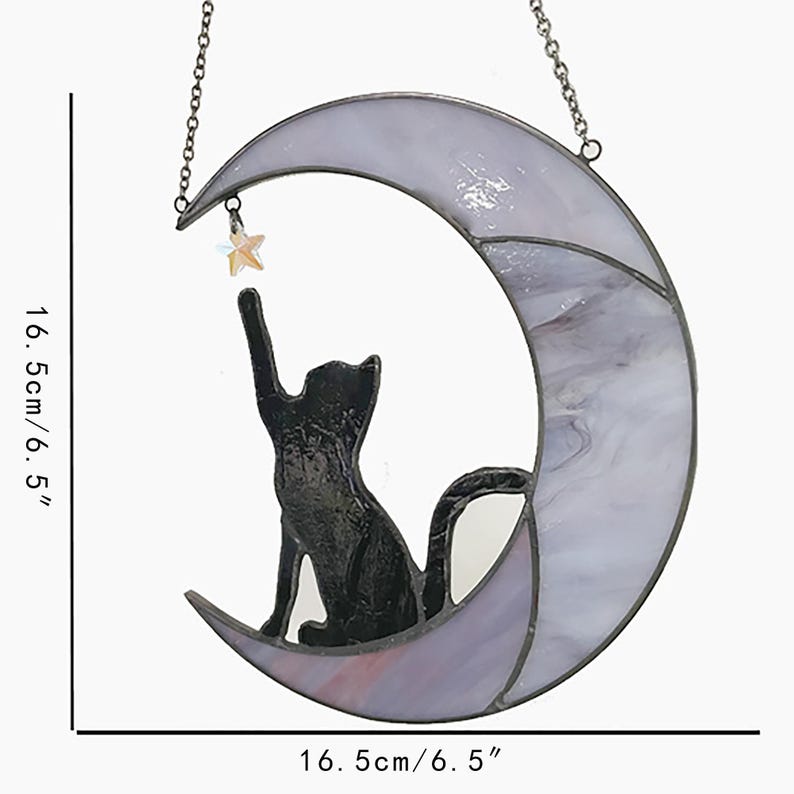 May include: A stained glass cat and moon hanging decoration. The black cat sits on a crescent moon, reaching for a star. The moon is 6.5 inches wide and 6.5 inches tall, with a lavender and white marbled design. A chain is attached for hanging.