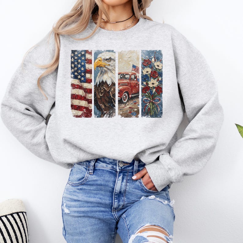 Puede incluir: Una sudadera gris claro con un dise&ntilde;o patri&oacute;tico. El dise&ntilde;o incluye la bandera estadounidense, un &aacute;guila calva, una camioneta roja y flores. El gr&aacute;fico est&aacute; dividido en cuatro paneles verticales con un aspecto envejecido y vintage.