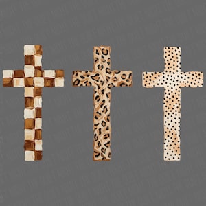 May include: Three decorative crosses with unique designs. One cross features a checkerboard pattern in shades of brown and cream. Another showcases a leopard print, and the third has a dotted pattern in tan and black.