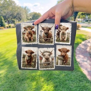May include: Dark gray t-shirt featuring six postage stamp-style images of Highland cows. Each image showcases a different cow with various accessories, such as floral crowns and bandanas, set against a rural backdrop with barns and fences.