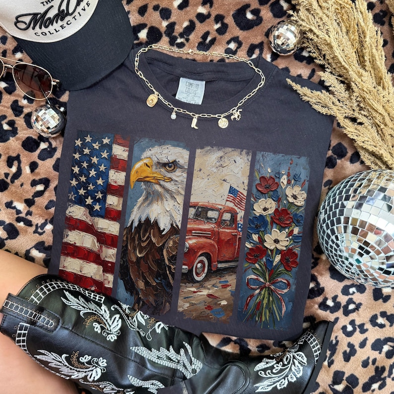 Puede incluir: Camiseta gris oscuro con un dise&ntilde;o patri&oacute;tico que presenta la bandera estadounidense, un &aacute;guila, una camioneta roja y flores. La camiseta est&aacute; adornada con un collar dorado, gafas de sol y una gorra negra. Tambi&eacute;n se ven botas de vaquero en blanco y negro.
