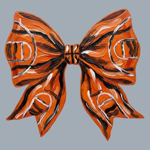 May include: An orange bow-shaped painting with black and white accents. The bow design incorporates basketball court elements, with the court lines and hoops visible. The artwork is set against a gray background.