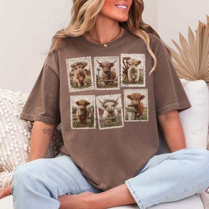 May include: Brown t-shirt featuring six postage stamp-style images of Highland cows. Each image showcases a different cow in a pastoral setting. The shirt has a relaxed fit and short sleeves, suitable for casual wear.
