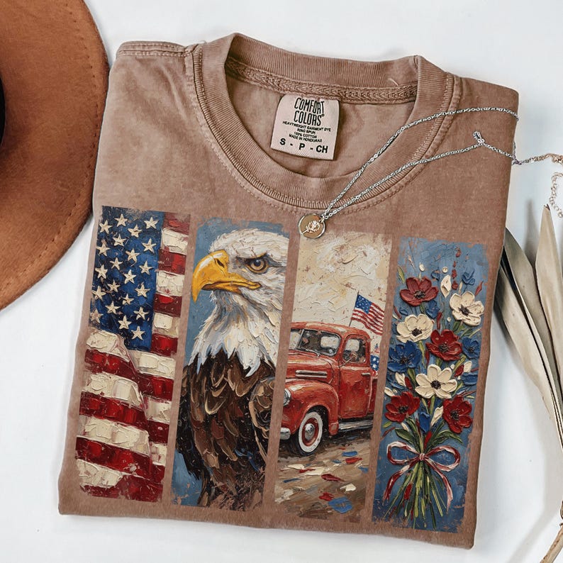 Puede incluir: Camiseta Comfort Colors marr&oacute;n con ilustraciones patri&oacute;ticas. El dise&ntilde;o incluye la bandera estadounidense, un &aacute;guila calva, una camioneta roja y un ramo de flores. Un collar plateado con un colgante est&aacute; sobre la camiseta.