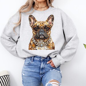May include: A light gray sweatshirt featuring a detailed illustration of a French Bulldog wearing leopard print glasses and a diamond chain. The dog's fur is a mix of brown and tan tones. The sweatshirt is a casual style.